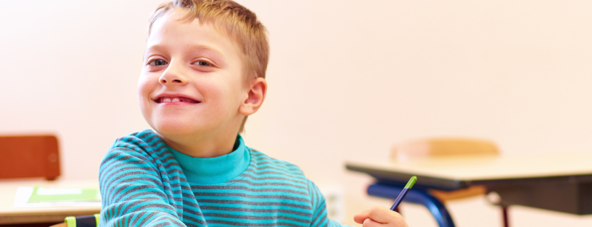 Happy child with a rare genetic disorder, sitting in a classroom