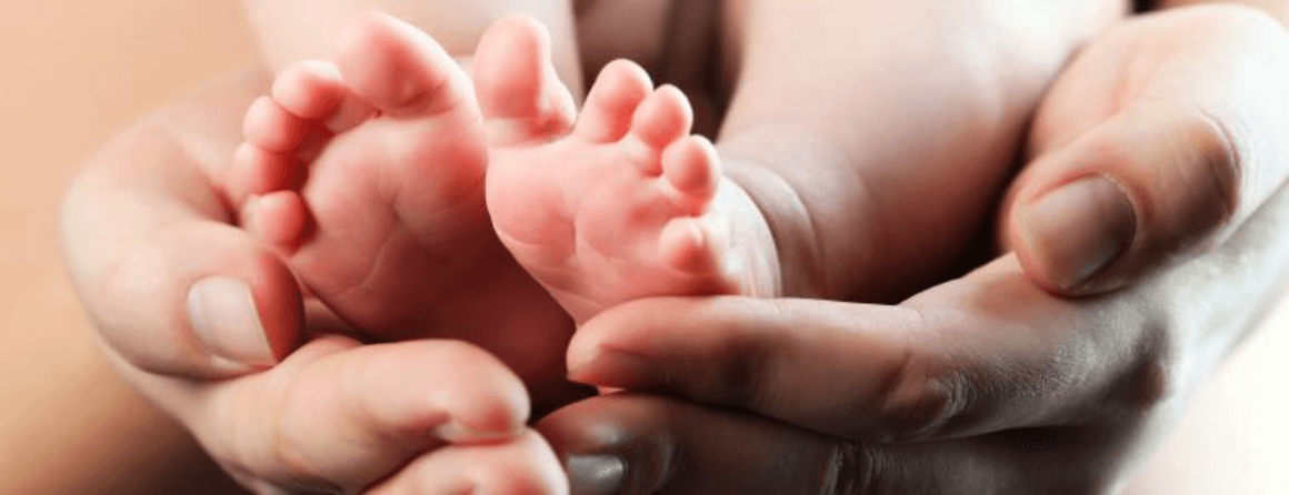 Woman's hands cradling an infant's feet
