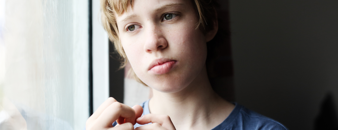 Pensive boy with autism looking out the window