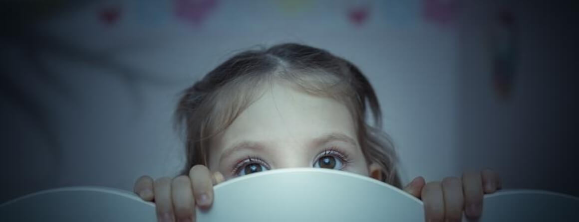 Young girl nervously looking over side of cot
