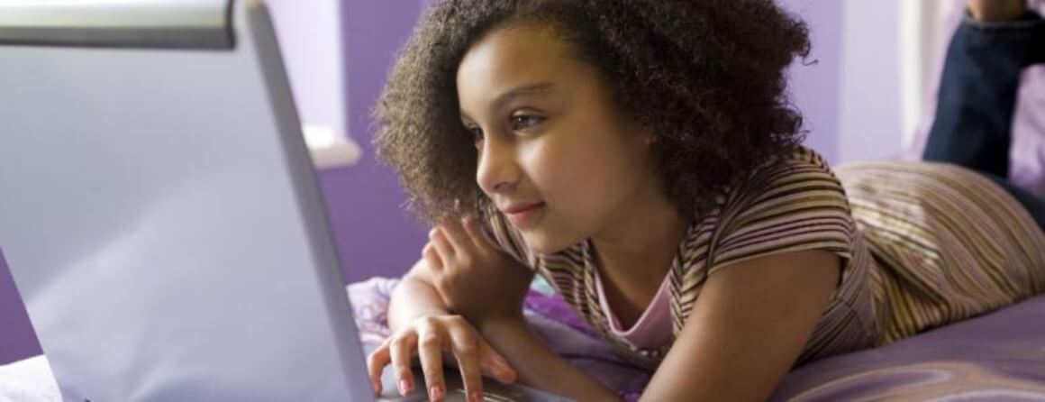 Girl lying on bed working on a laptop