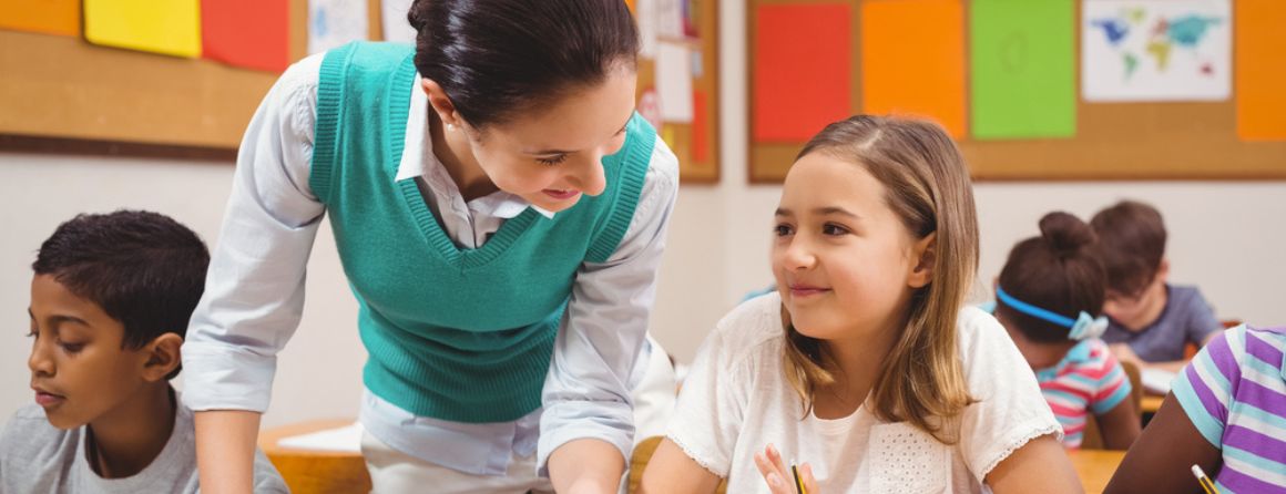 Teacher helping a little girl during class at the elementary school