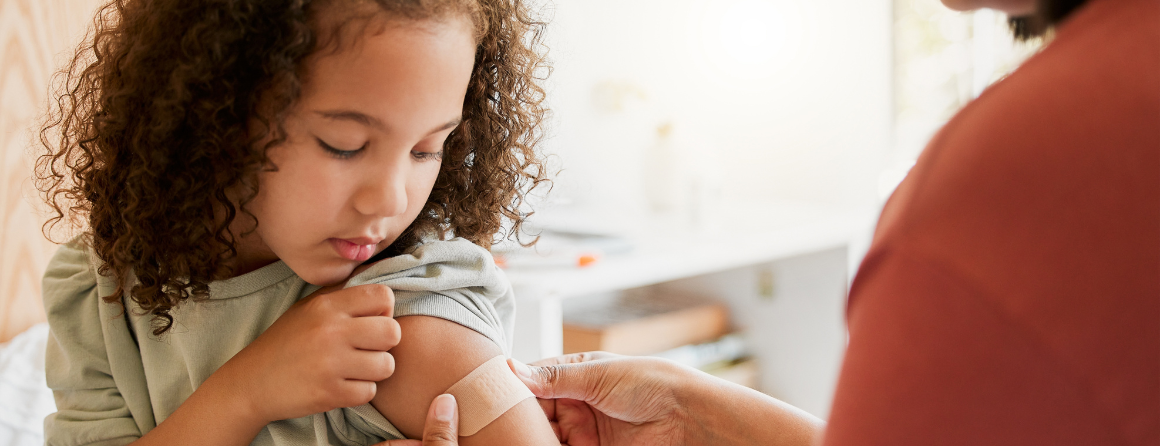 Nurse vaccinating child putting a bandage on at a clinic