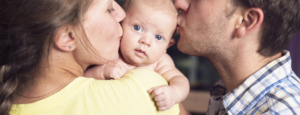 A baby held by a mother and father