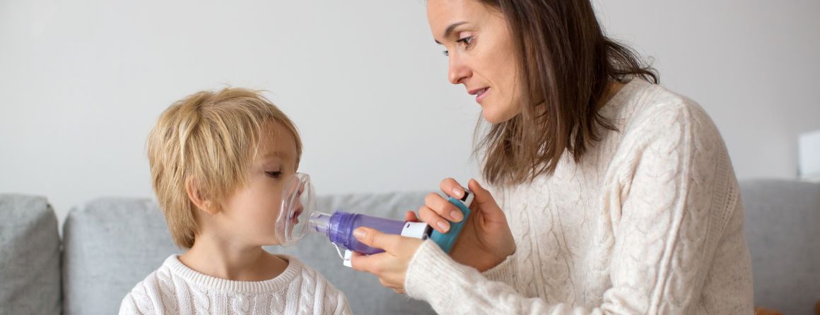 Child being given asthma puffer by parent