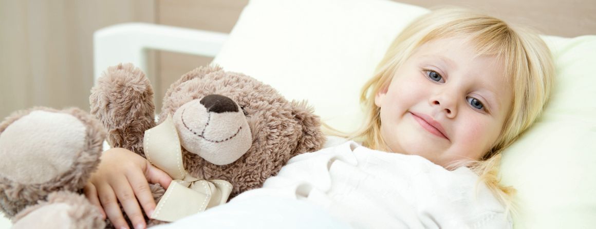Girl in bed holding stuffed animal