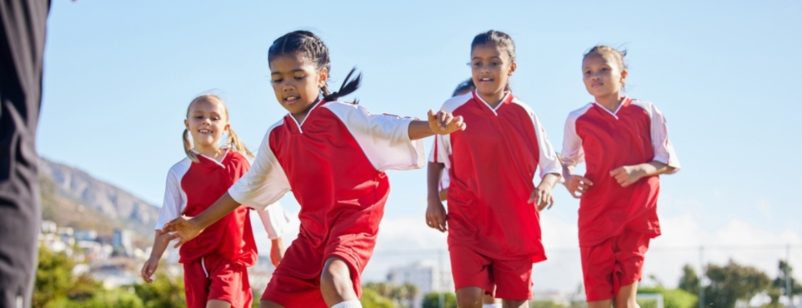 Four young children are playing soccer