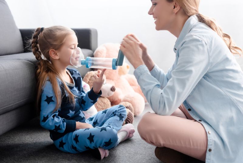 Girl taking asthma puffer and spacer