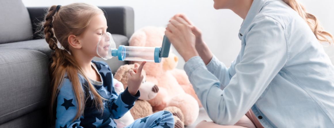 Girl taking asthma puffer and spacer