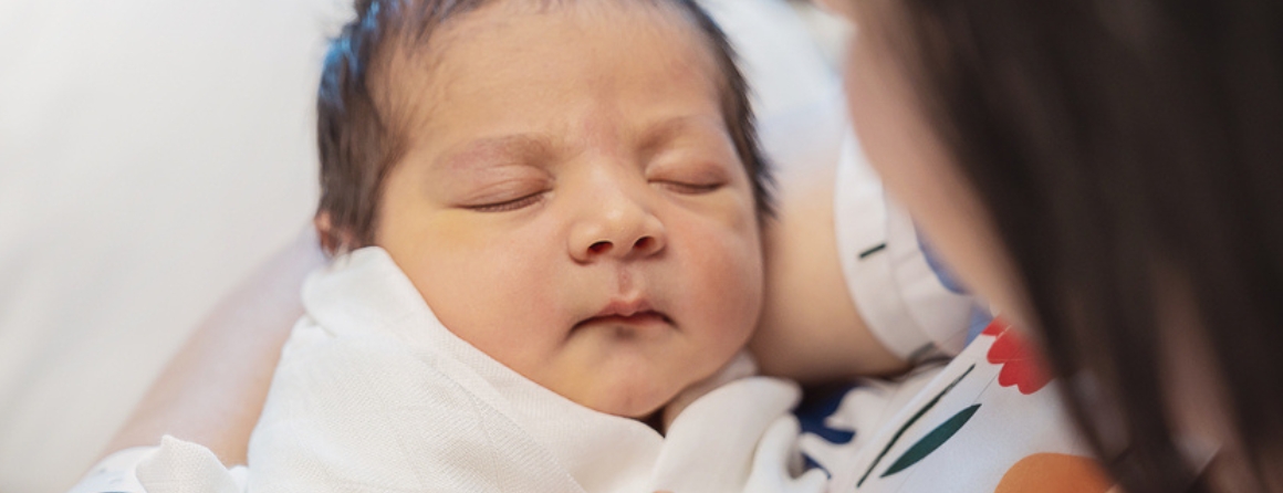 A newborn baby held by a mother