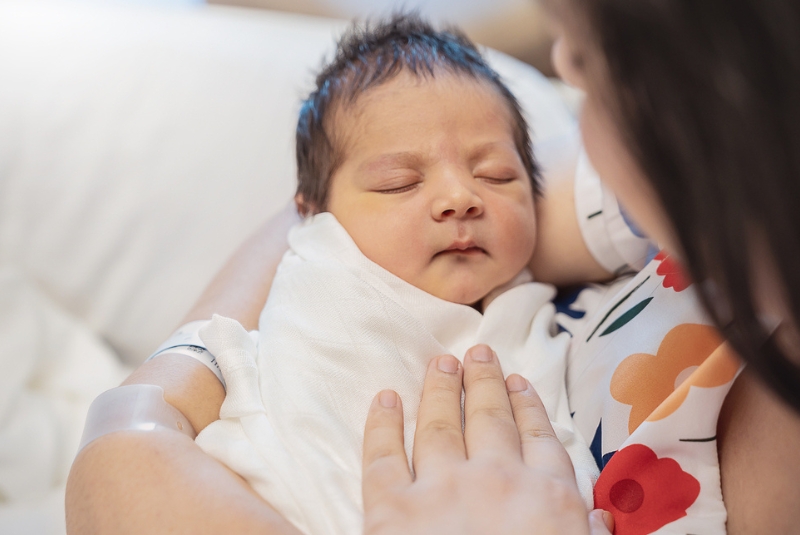 A newborn baby held by a mother