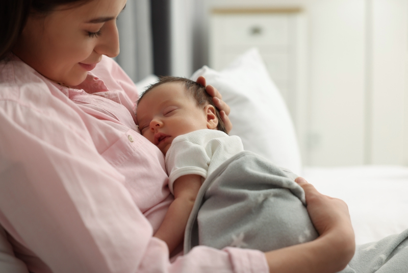 A preterm baby held by a mother
