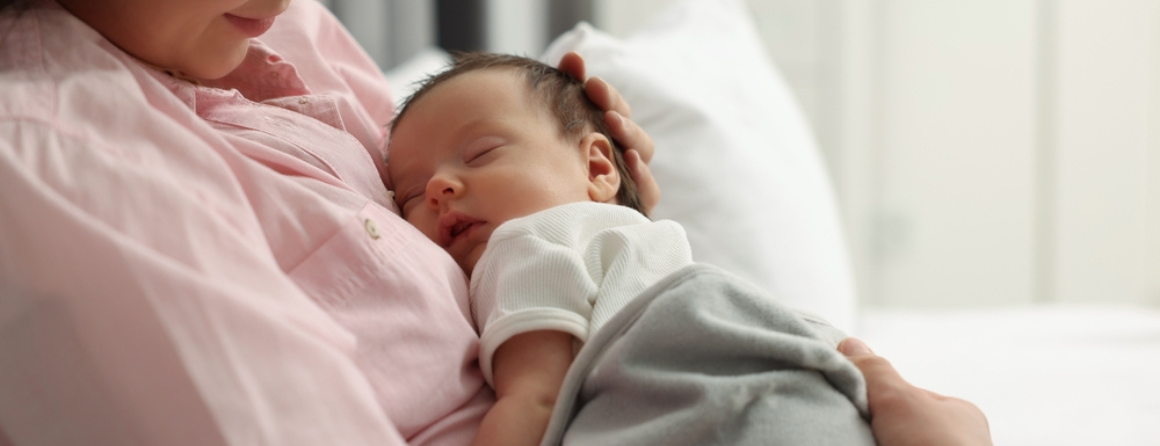 A preterm baby held by a mother