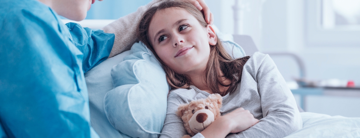 A child with cancer in hospital with a woman and teddy
