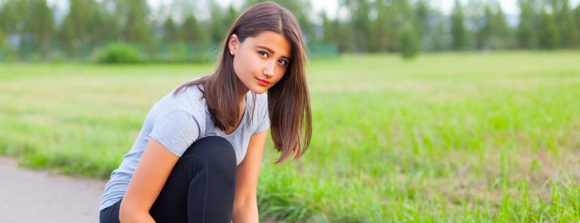 Athletic teenage girl in park lacing up her shoelaces 