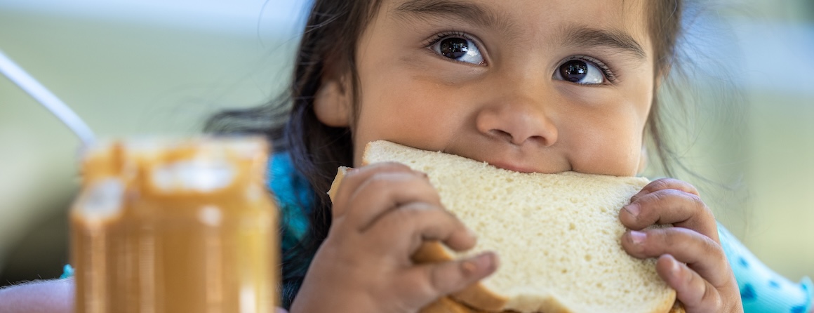 A child eating a peanut butter sandwich, a common allergy trigger