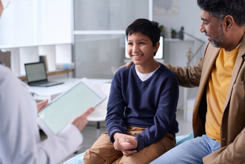 Boy smiling with his dad and doctor