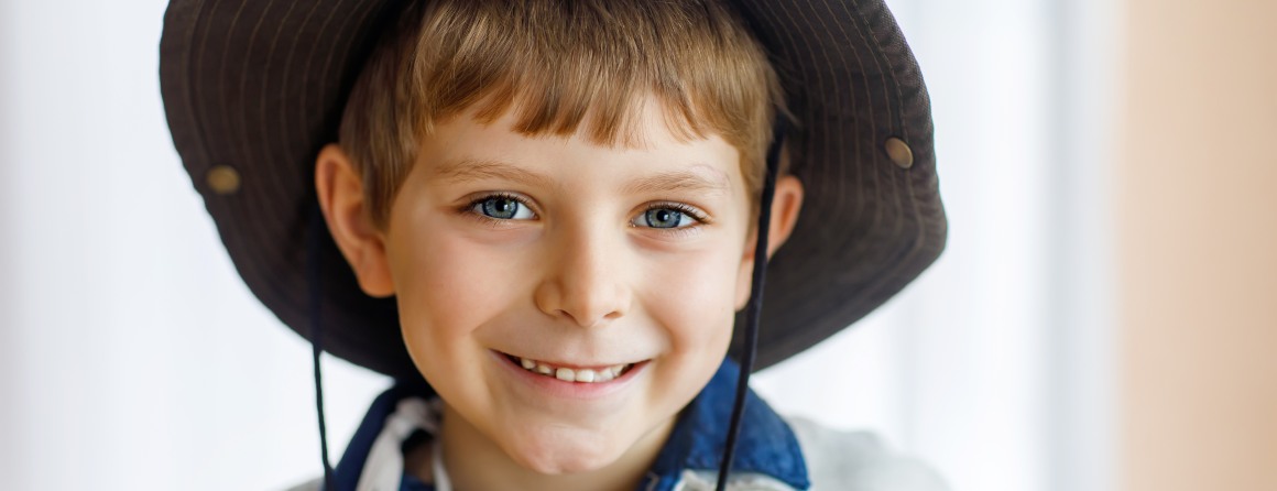 A primary-school aged boy weaing his uniform and a broad-rimmed hat.