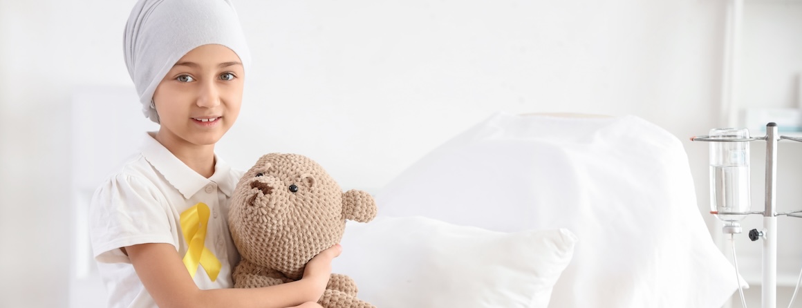 A child in a hospital bed with a teddy bear
