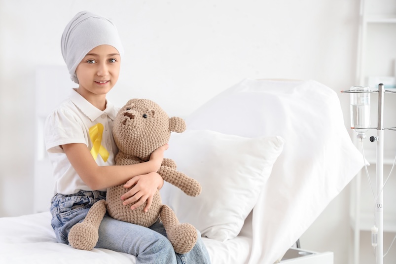 A child in a hospital bed with a teddy bear