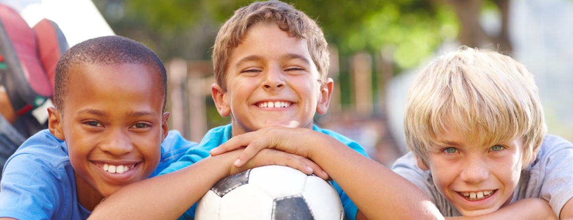 Three boys smiling with a soccer ball