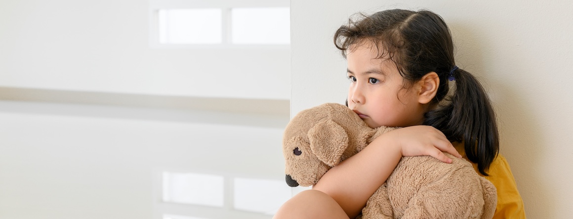 An anxious-looking child with a teddy bear