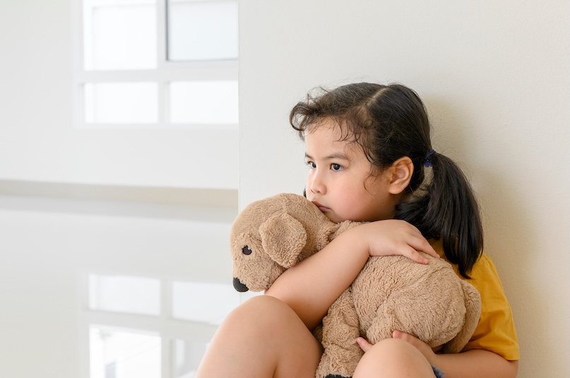 An anxious-looking child with a teddy bear