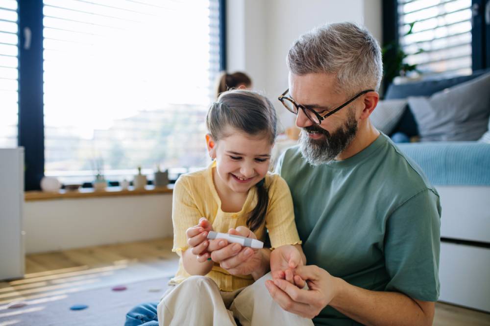 child checking blood sugar with parent