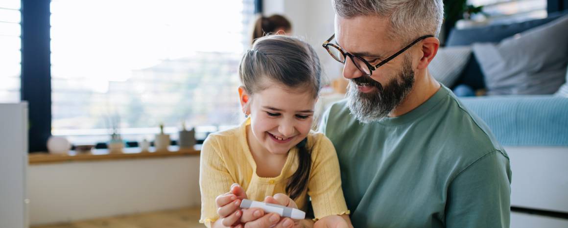 child checking blood sugar with parent