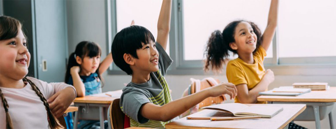 Two children raising their hands in the classroom