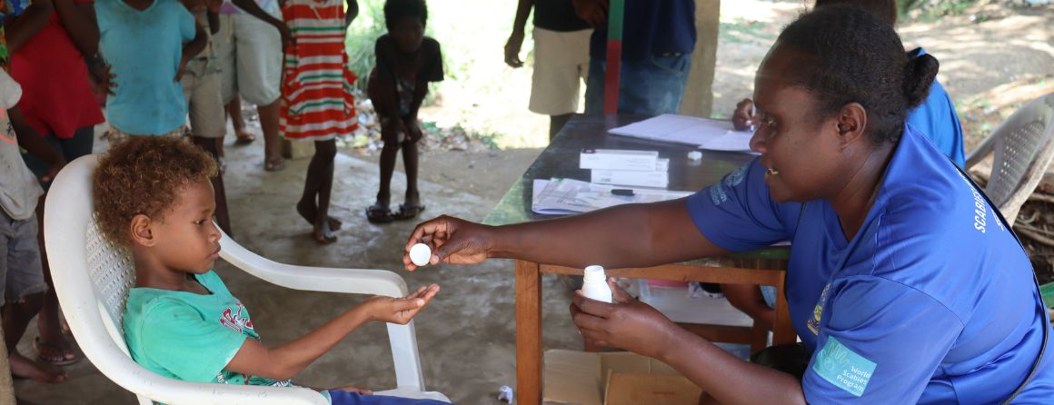 HCC Registered Nurse Delmay Kovo giving a scabies tablet to 7 yr old 