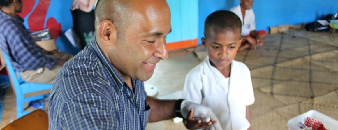 Healthcare worker holding hand of young boy.