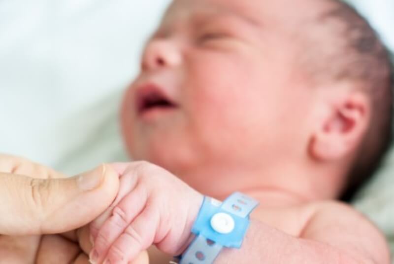 Person holding the left hand of a newborn infant