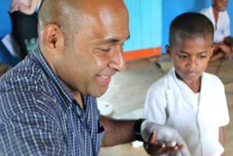 Healthcare worker holding hand of young boy.