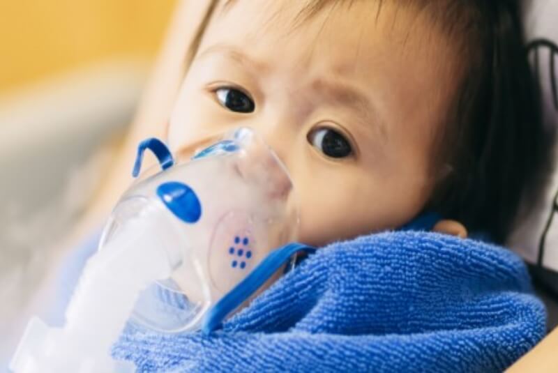 Infant wearing an oxygen mask over their mouth and nose