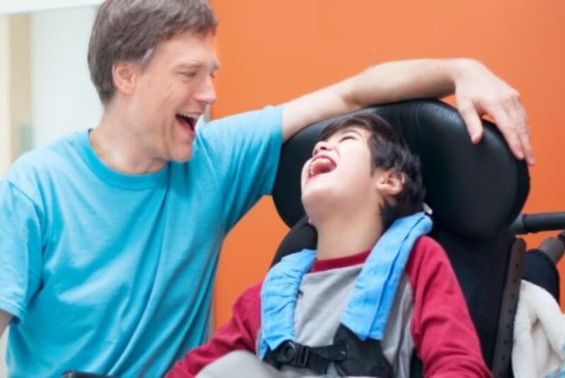 Man and boy in cerebral palsy wheelchair laughing