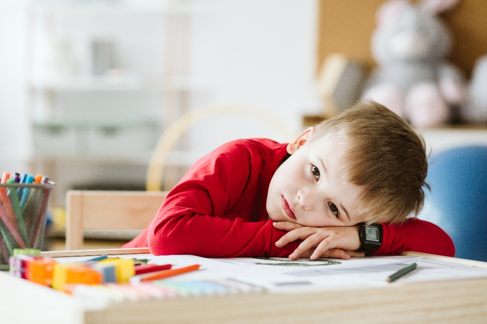 Sad child with ADHD resting head on table