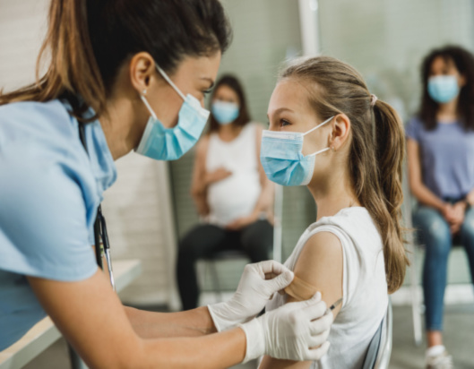 Nurse puts a band aid on a girl after COVID-19 vaccine