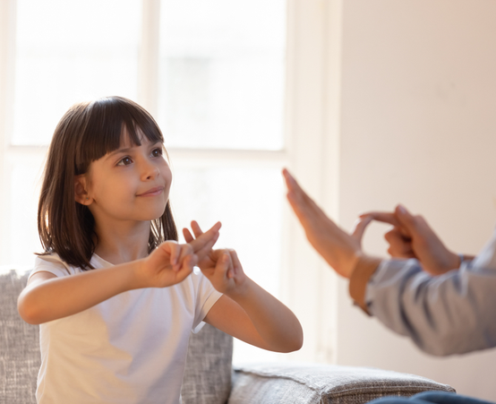 Little girl with brown hair being taught sign language