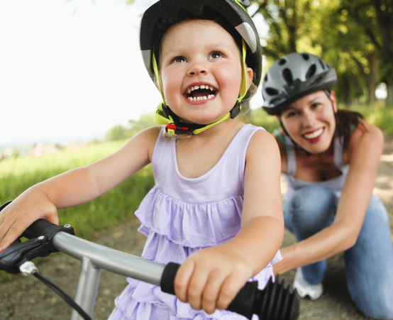 child and mother riding bike with helmets on