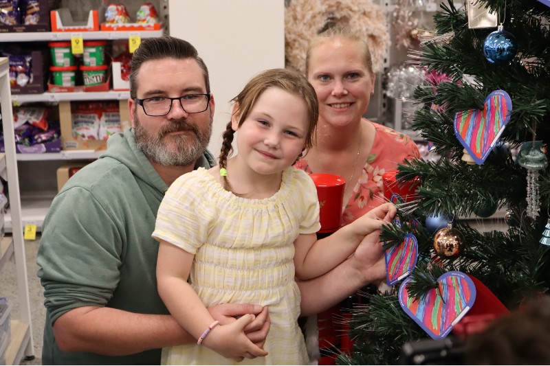 Emily with her family in front of a Christmas tree with Big W hearts