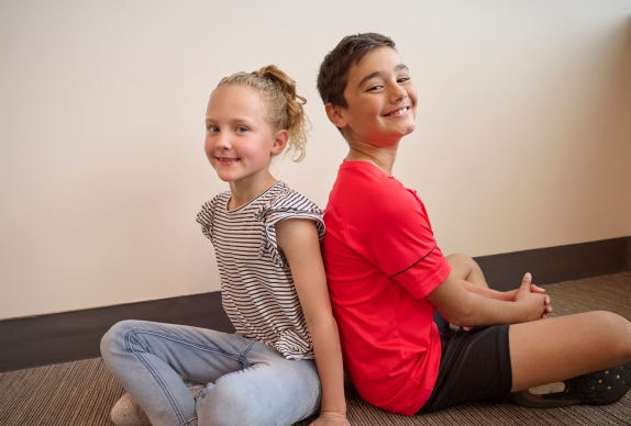 Two children sitting back to back