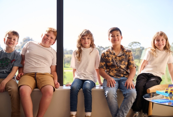 5 adolescents sitting smiling