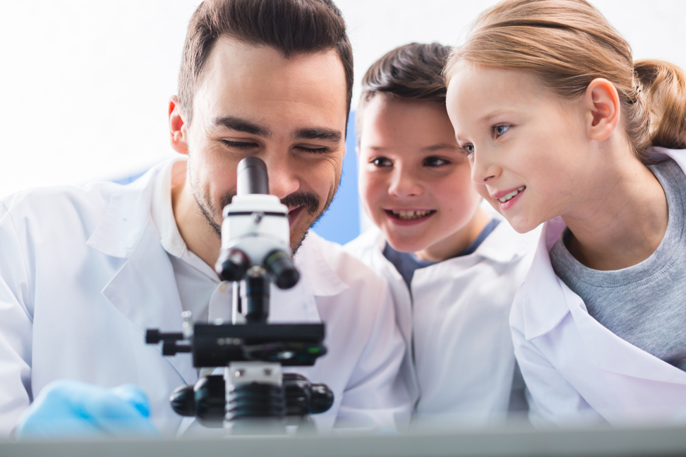 Adult and children looking through microscope