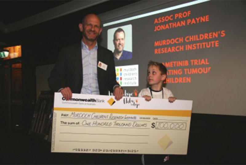 Dr Gabriel Dabscheck (Royal Children’s Hospital) accepting a cheque on behalf of MCRI from Billy at the 2022 Kicking Butt for NF Research event.