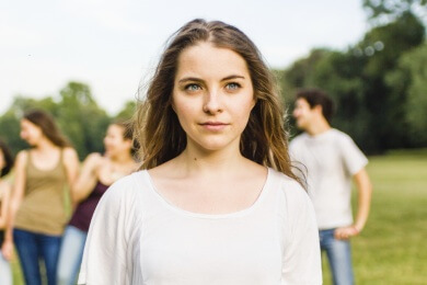 Teenage girl standing apart from a group of teenagers