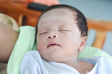 Infant sleeping in someones arms
