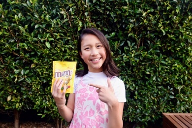 Stella Ng holding up a bag of peanut M&Ms