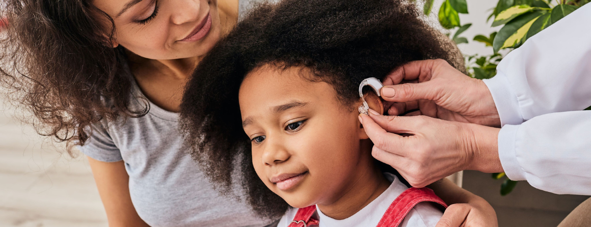 Yioung girl with mother and audiologist, getting hearing aids fitted