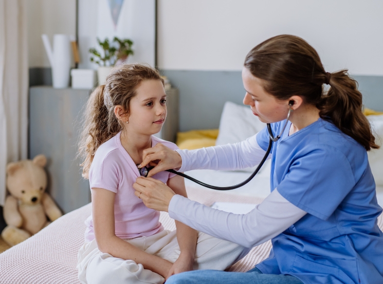 A young girl has her lungs checked by a doctor